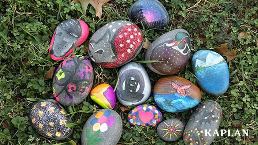 An image of painted stones laying in the grass. 