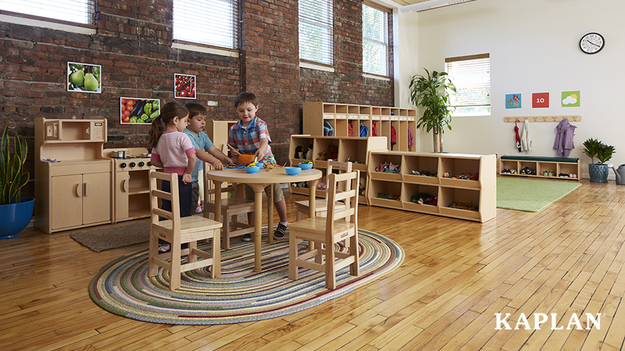 Three preschool children pretend to cook a meal in the dramatic play center in their classroom.