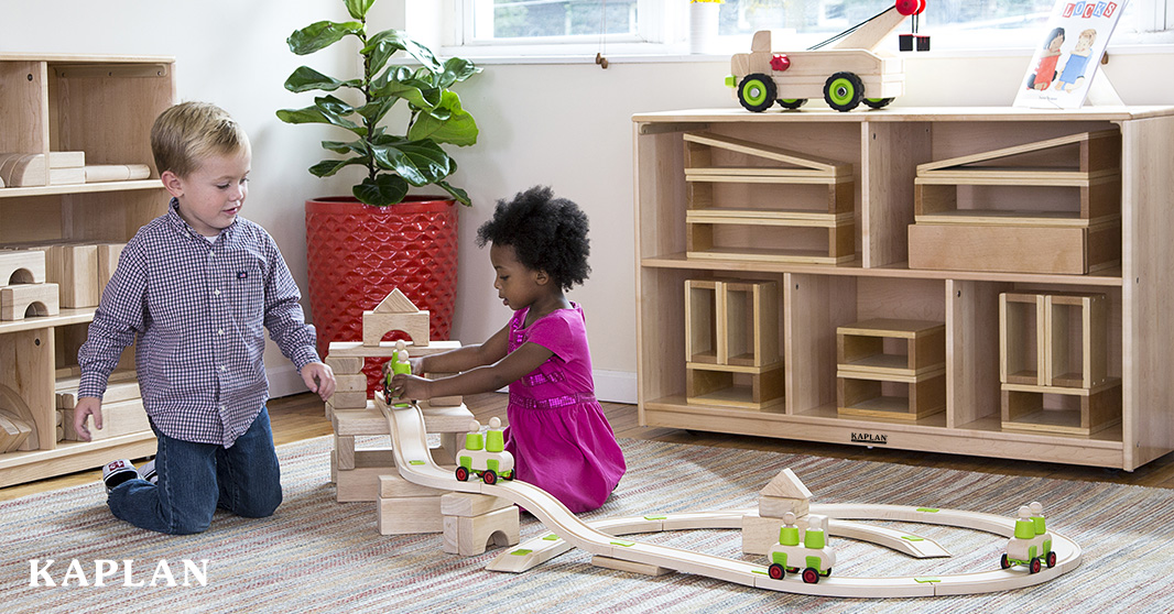Two children engaged in block play in front of a maple storage compartment.