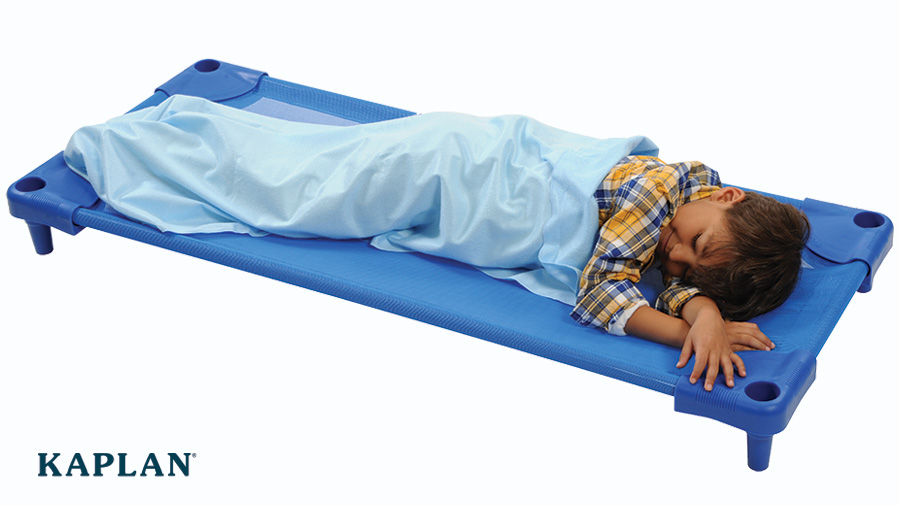 A preschool-aged boy takes a nap on a blue cot