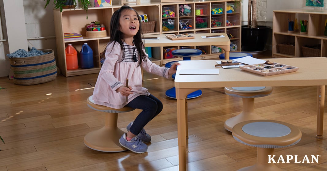A young girl seated on flexible seating at a classroom table in an early childhood classroom.