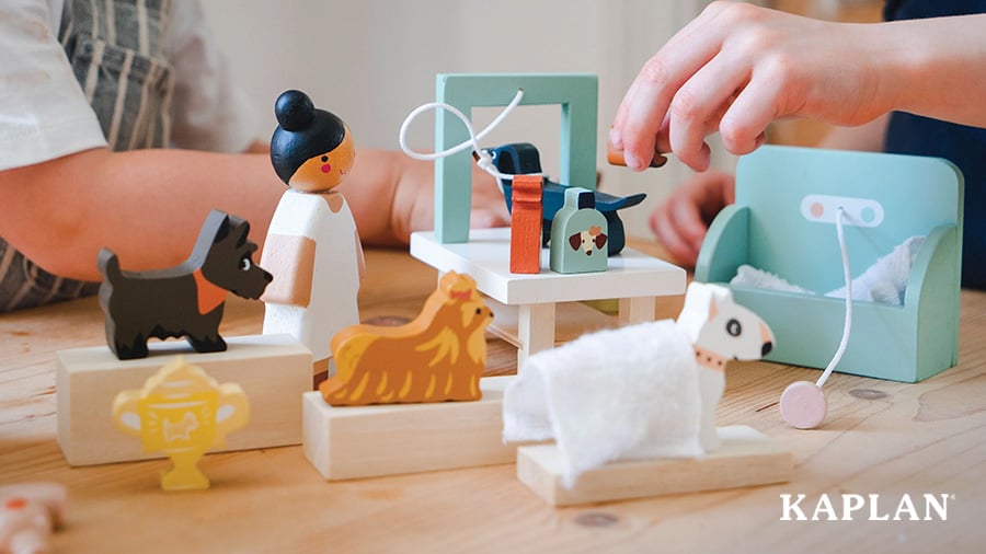 An image of children's hands moving as they play with characters in the Waggy Tails Dog Salon. 