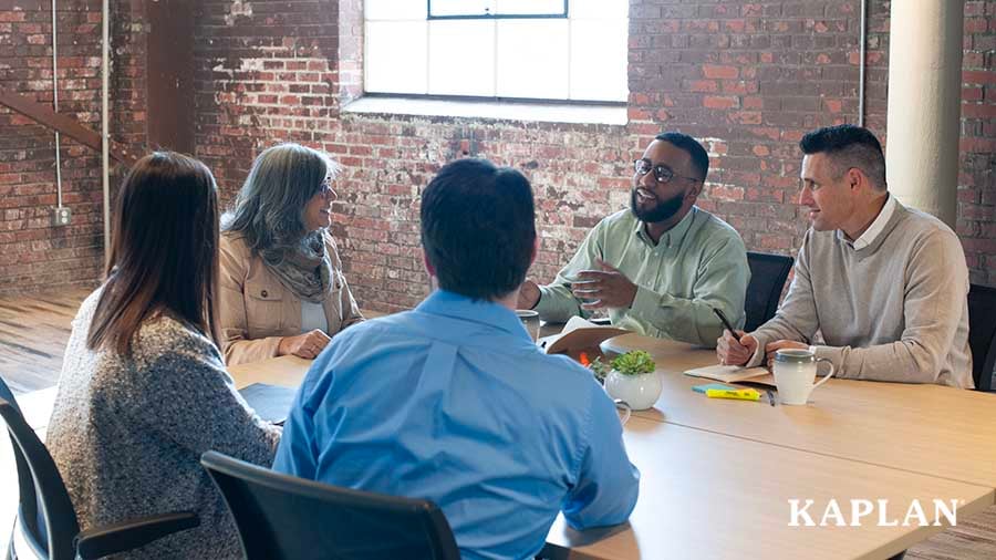 A group of early childhood professionals sit around a table in a meeting room.