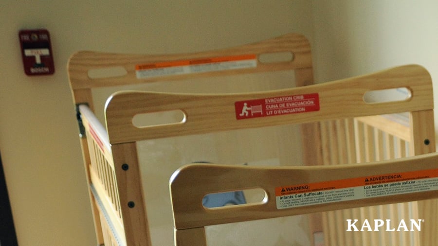 A red sticker on a safety crib indicating that it is an evacuation crib used to transport infants out of the building during an emergency.