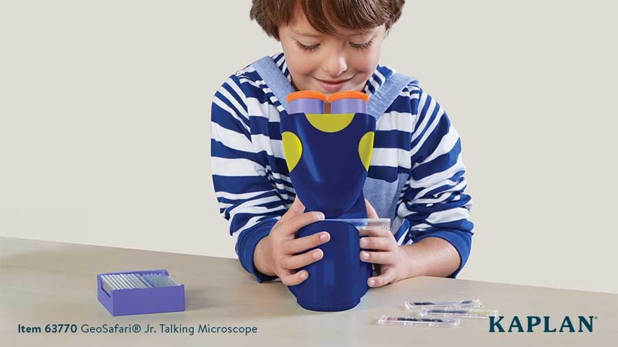 A young boy looks through the lens of the GeoSafari Jr. Talking Microscope.