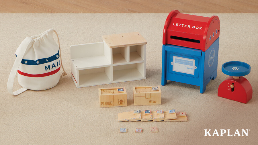 An image of the Special Delivery Mail Set on a playroom carpet, in the image is a mailbox, five letters with stamps, two packages with stamps, a scale, a mail bag, and a service counter. 