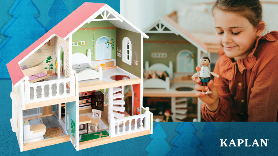 A young girl holds a wooden doll in front of the Country Cottage Wooden Doll House. 