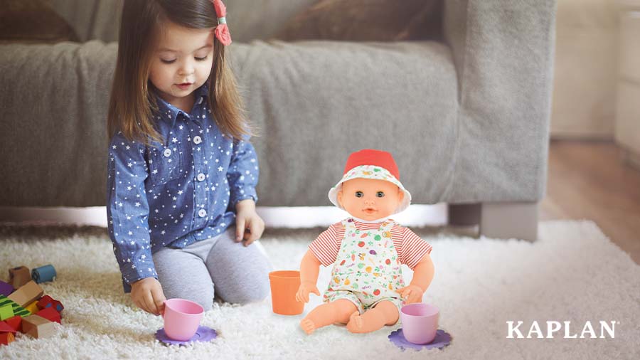 A young girl is sitting on the floor with a Water Fun Calypso Doll. The girl is reaching down to pick up a pink plastic tea cup, another pink tea cup is sitting beside the Calypso Doll. 