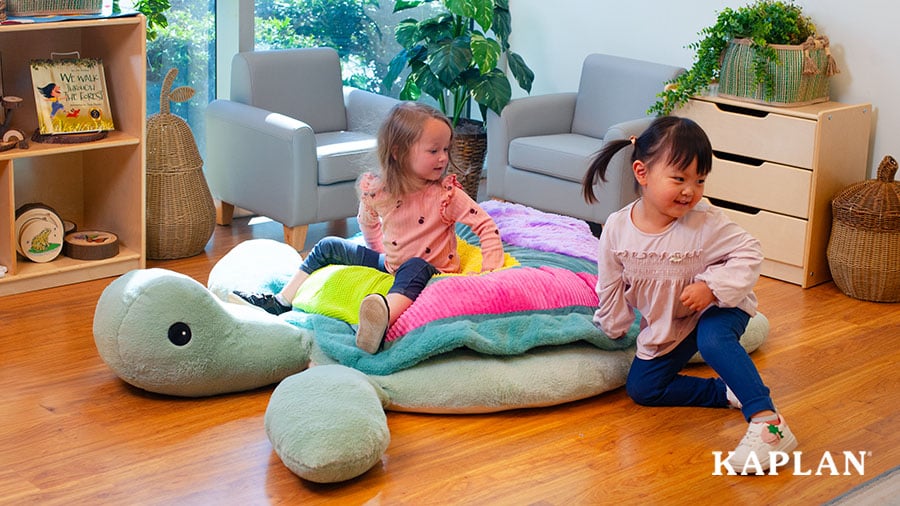 Two young children sit on Sunny the Giant Sensory Turtle in an early childhood classroom.