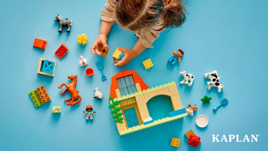 An overhead image showing a young child building with a set of LEGO DUPLO Caring for Animals at the Farm.