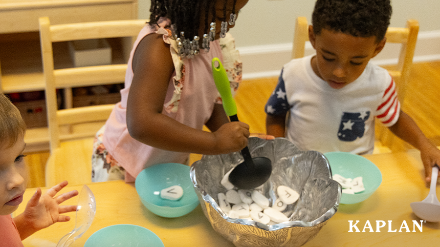 Young children use plastic spoons to stir alphabet stones while participating in the Making Stone Soup activity. 