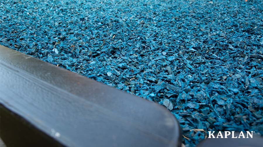 Close-up of (blue) loose-fill rubber mulch against a black playground border