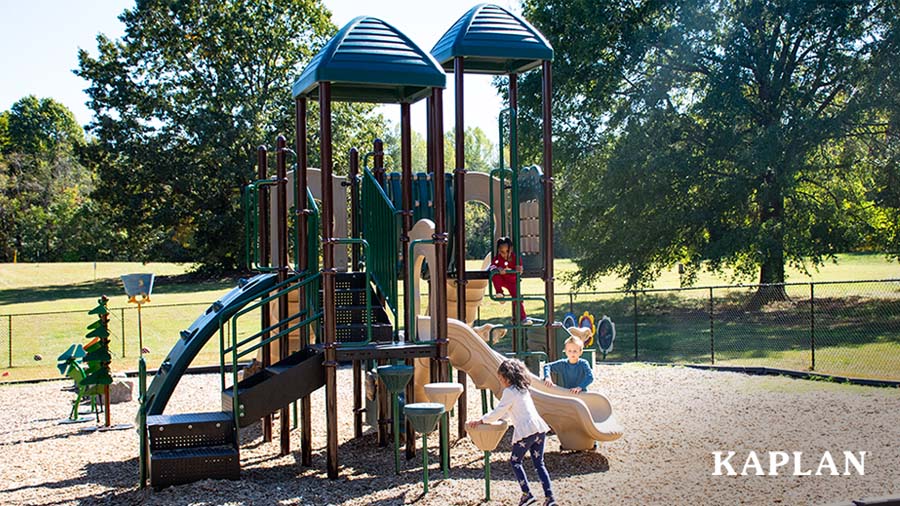 An image of children playing on an early childhood playground, which contains large playground equipment, Kaplan Chalkboard Flowers, and Kaplan Musical Flowers. 