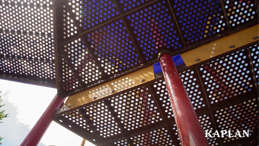An up-close image of the underside of a large piece of playground equipment, showing bolts that hold the walkway together. 