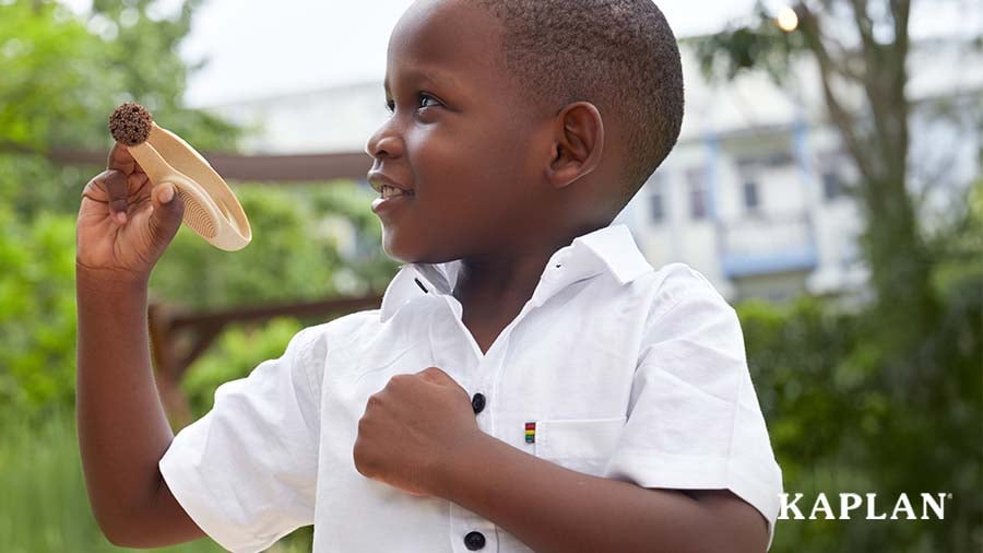Child using tweezers to pick up an object while outdoors