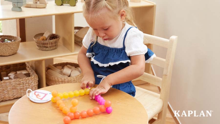 Child playing with multicolored tactile toys at a wooden table