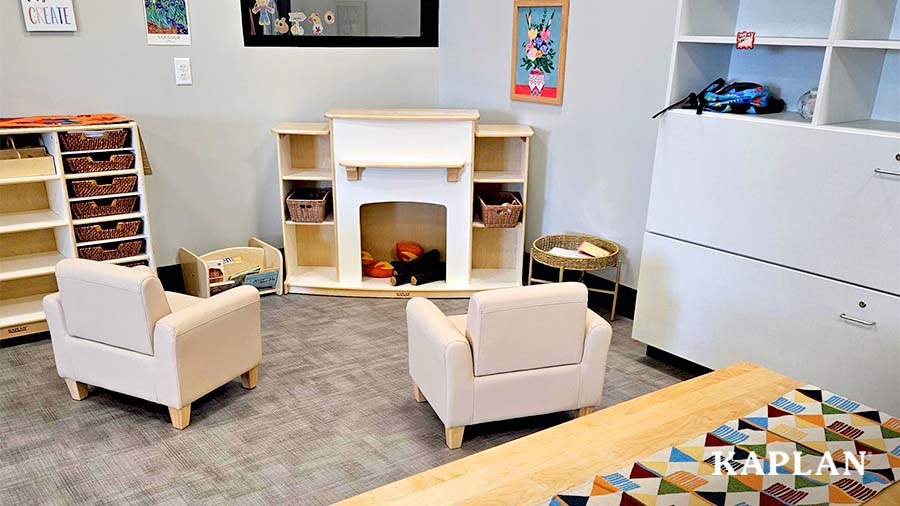 A cozy corner in the Goodwill Excel Center's drop-in child care space which features the Sense of Place Fireplace and cozy beige chairs. 