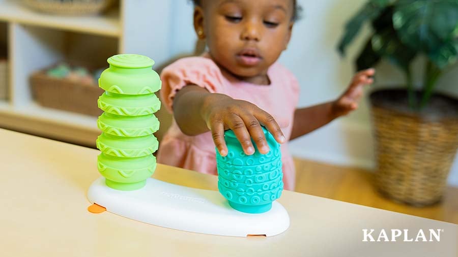 Young child stacking colorful sensory toys