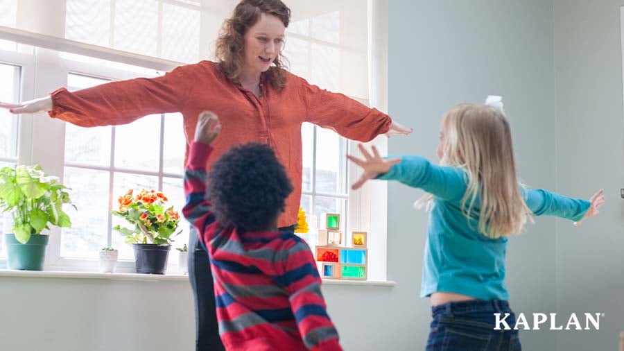 Early childhood educator leading two children in a movement activity