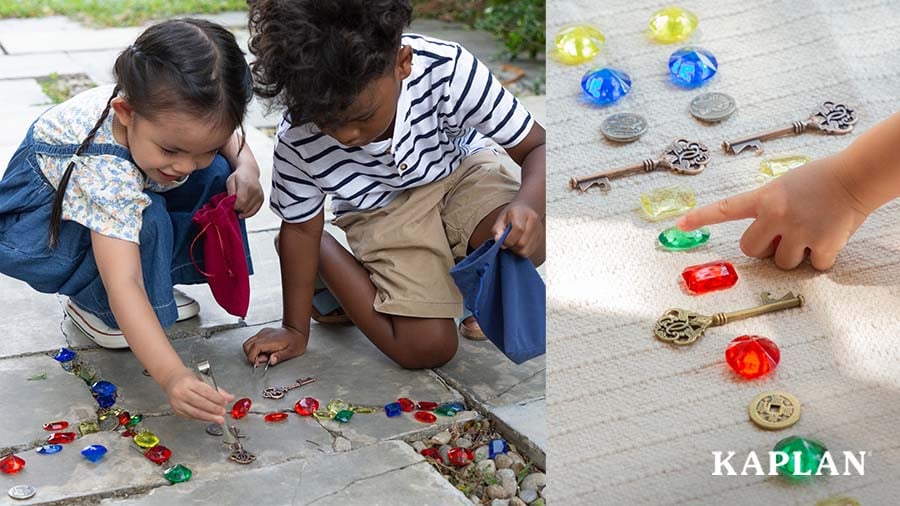 Two children pick keys and gems up off the ground with small pairs of tongs and put them in small drawstring bags