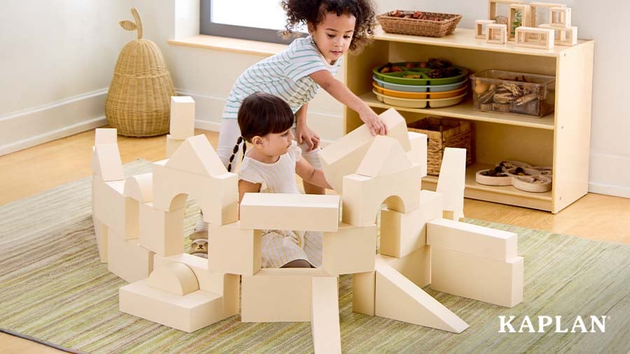 Two children on the carpet building structures with large blocks
