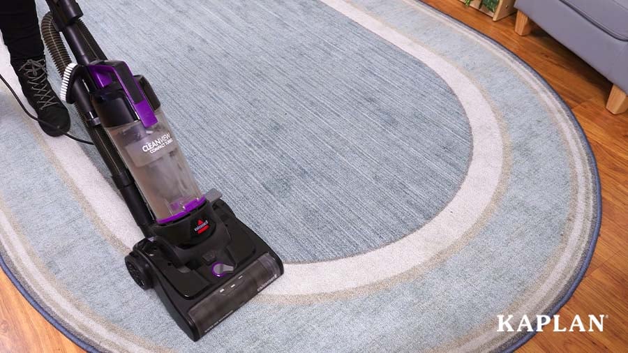 A vacuum cleaner removes debris from a blue classroom rug. 