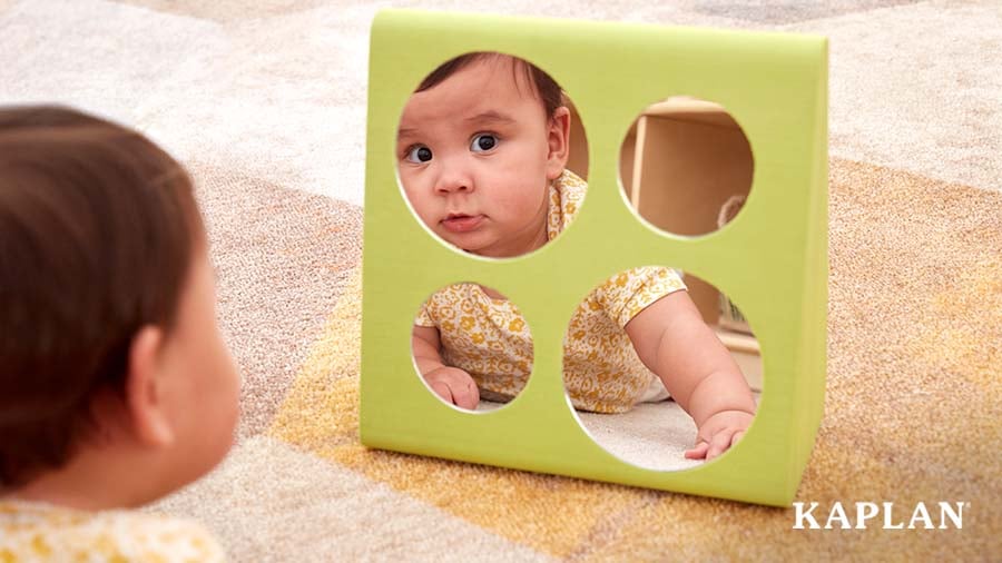 Infant on carpet looking in a mirror during tummy time