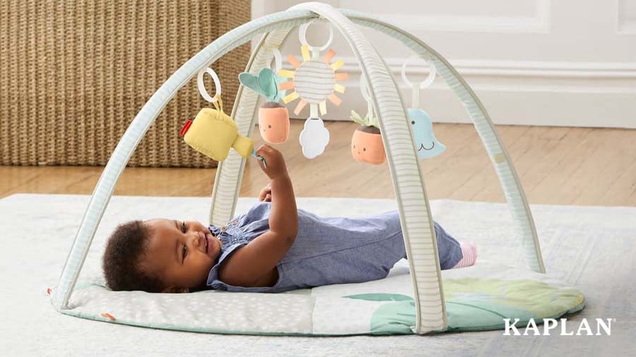 Infant playing with overhead gym on carpet