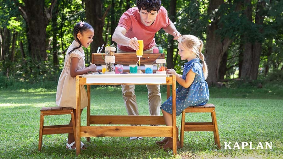 Early childhood educator with children making crafts outdoors 
