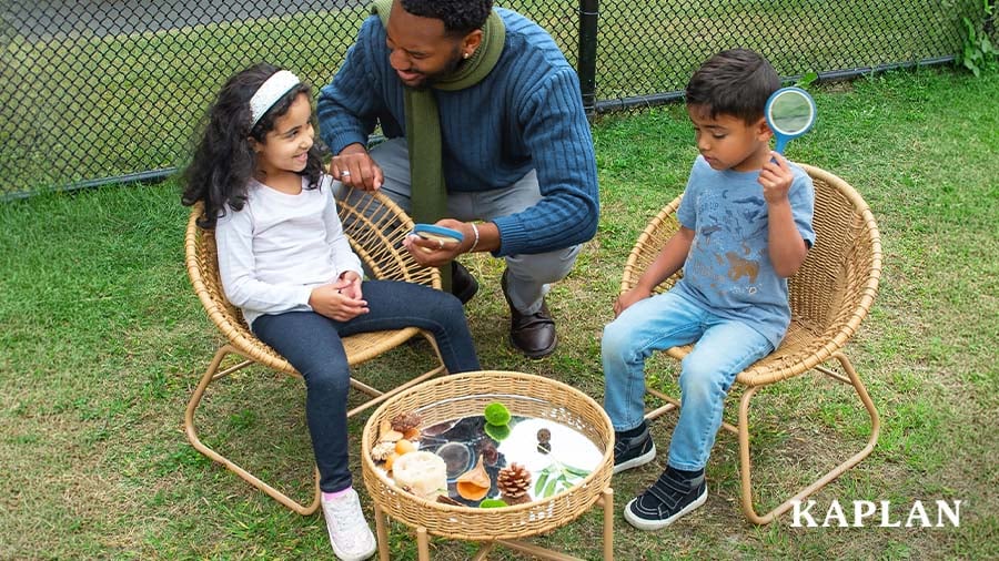 Early childhood educator with children sitting in outdoor wicker furniture