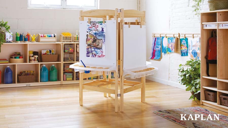 A four-sided art easel stands in an early childhood art learning center. 