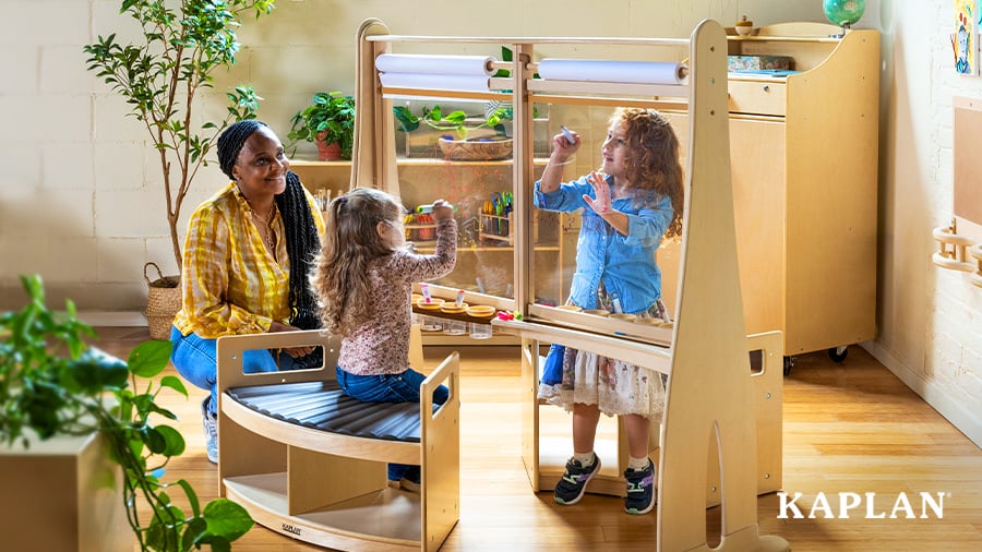 wo young children creating artwork at an accessible art easel alongside an early childhood educator