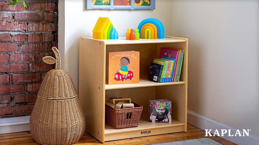 Low wooden bookshelf with children's board books in a classroom reading area