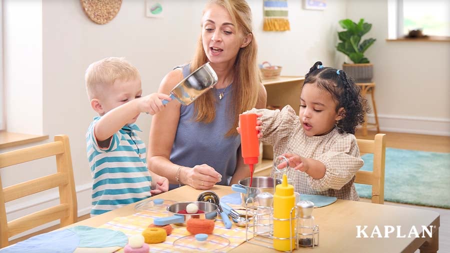 Early childhood educator guides two young children in pretend cooking play