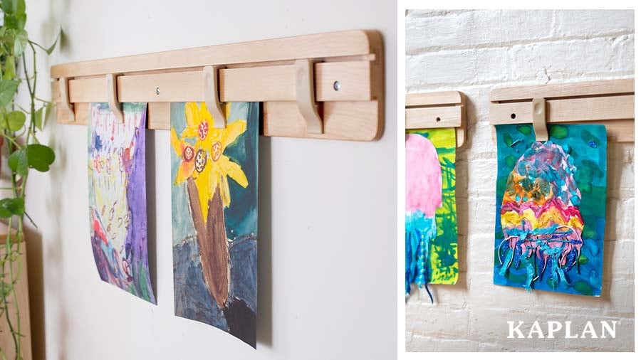 Wall-mounted display rack holding children's paintings in an early childhood classroom