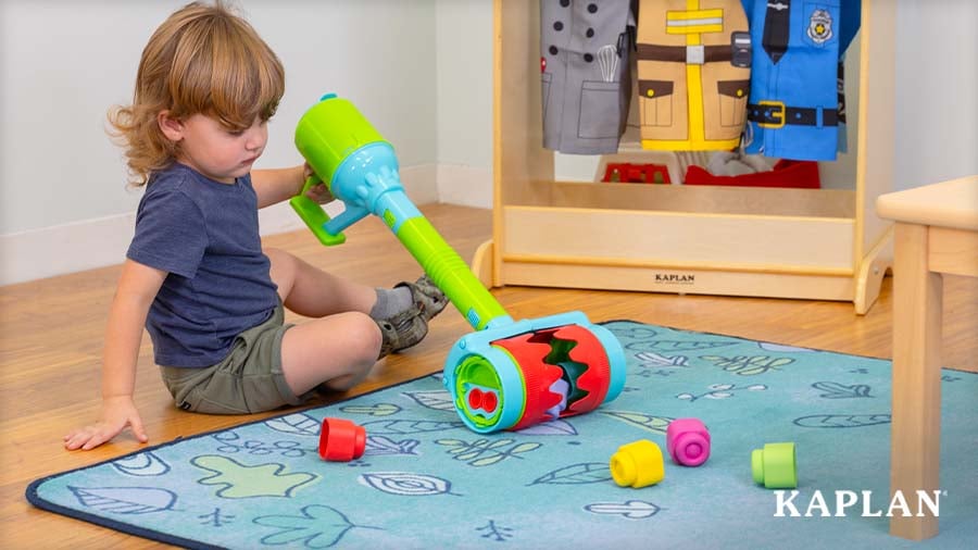 Preschooler using a Soft Clemmy Sensory Roller Vacuum to pick soft blocks in the dramatic play area