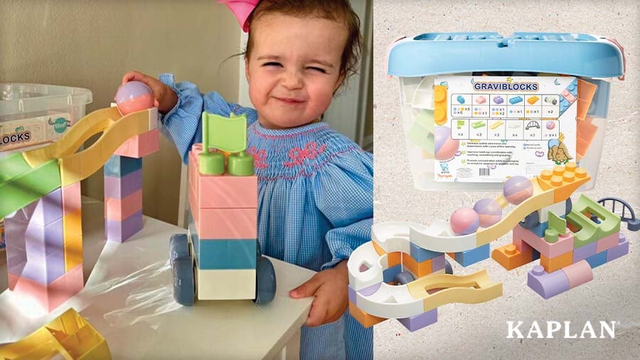 A smiling toddler places a ball at the top of a GraviBlocks Toddler Ball Run, shown shown beside the full set and storage tub