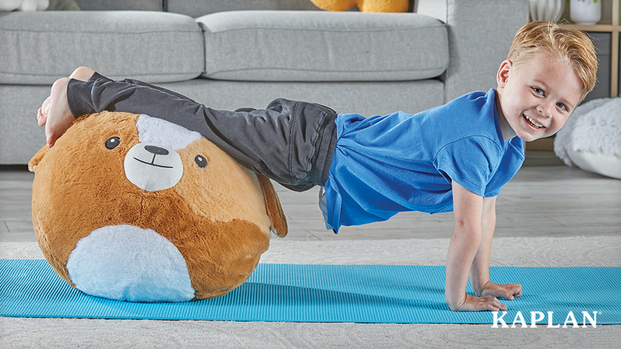A smiling child balancing his body horizontally with the BubblePlush Yoga Ball Buddy