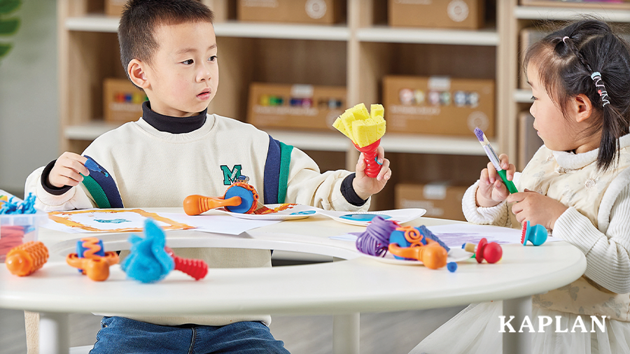 Two young children using tools from the Art Toolkit Set to create artwork