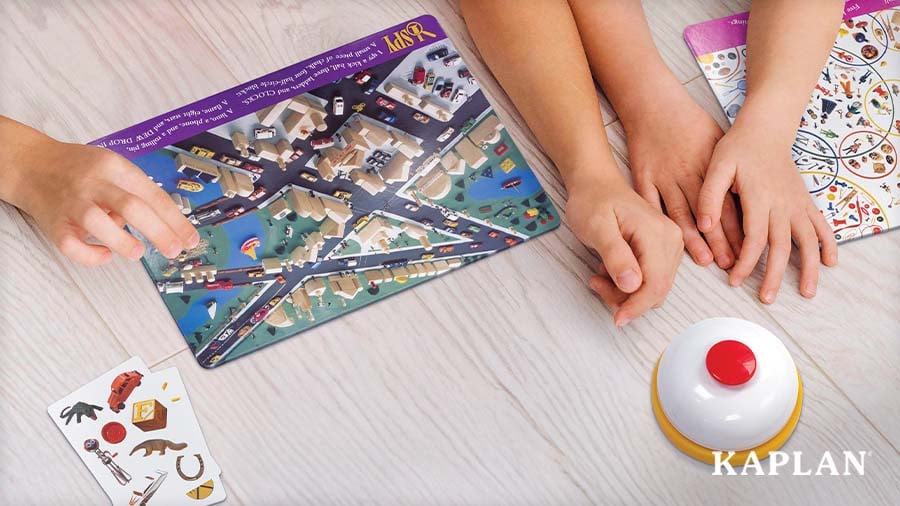 View of children’s hands playing I SPY Eagle Eye Find-It-Game with picture cards and a tap bell