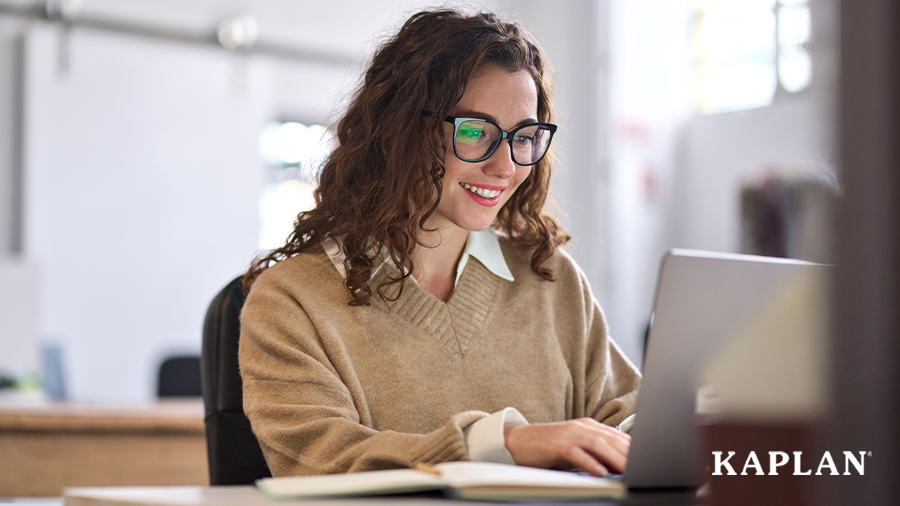 A woman looks down at a laptop while smiling. 