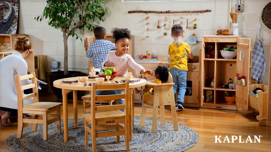 Young children playing in a wooden Kaplan play kitchen set