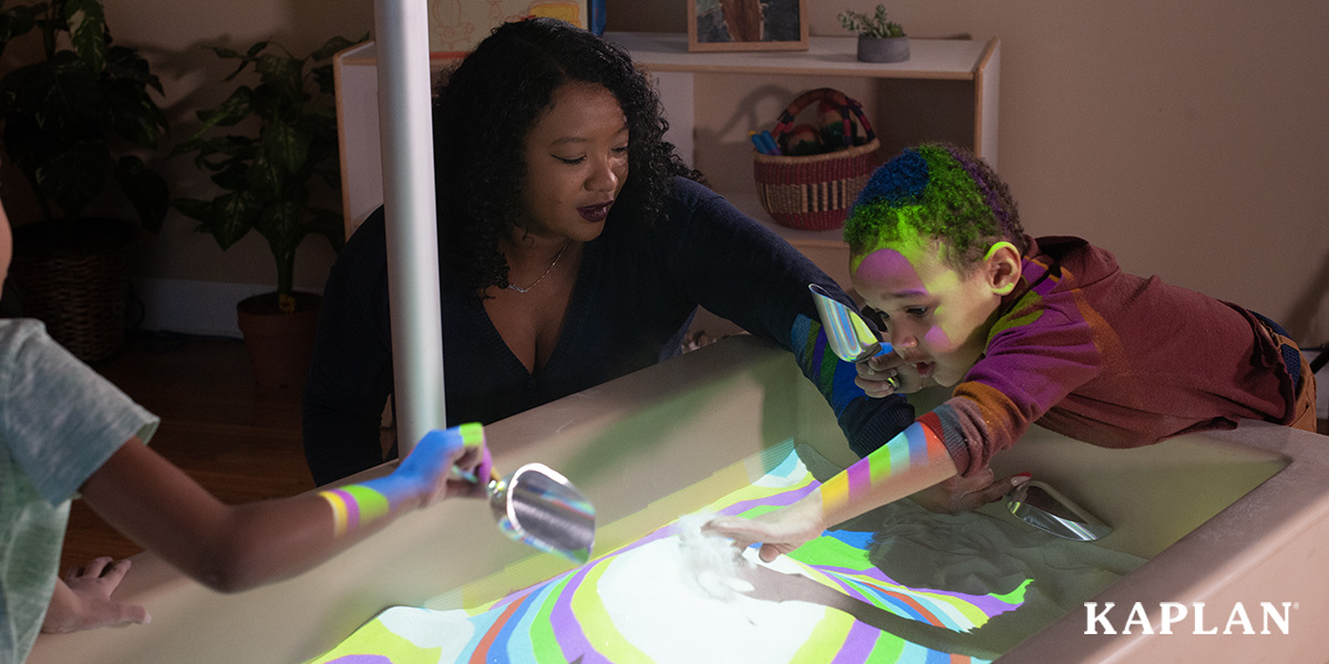Featured image: A young boy leans over the side of a sand table lit up with topographical projections, while a female teacher and a young girl dig in the sand.  - Read full post: 4 Considerations for Choosing the Right Technology for Your Classroom
