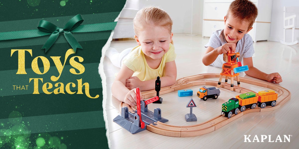 Featured image: Two young children sit on a hardwood floor, smiling as they play with a wooden train set.  - Read full post: 10 Must-Have Toys for Children 5 Years and Older