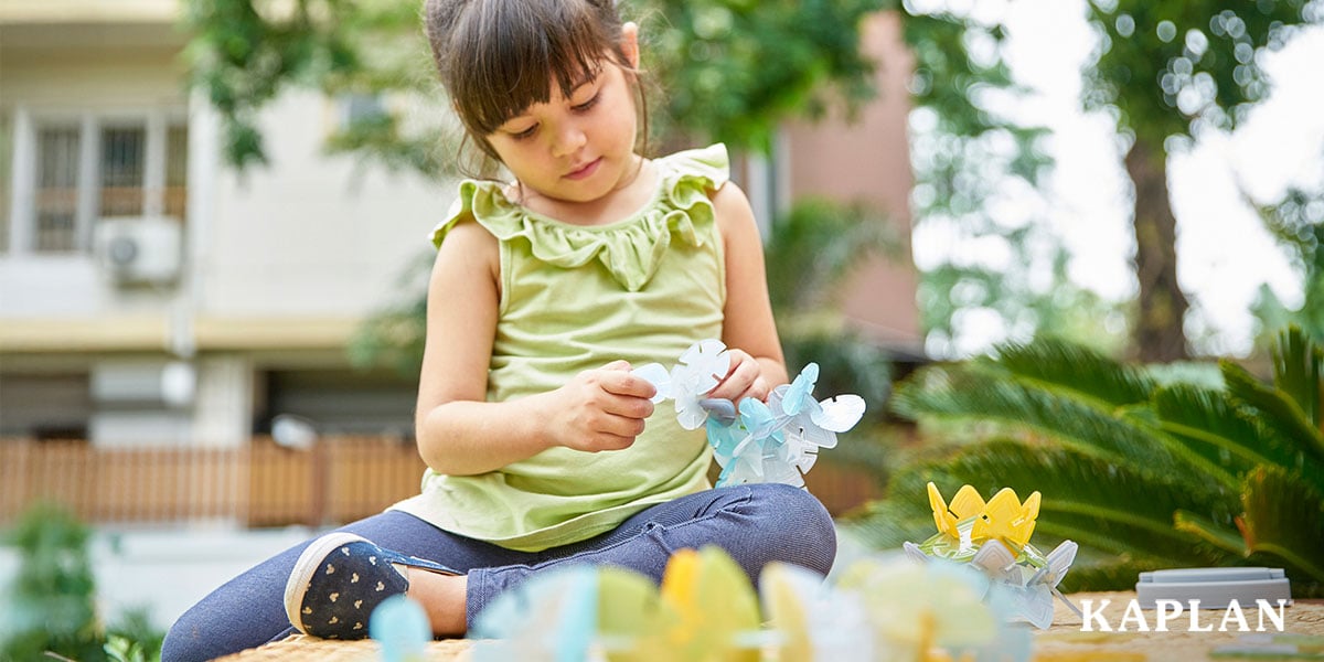 Featured image: Child in green shirt playing outside with building toys - Read full post: 7 Must-Haves to Prepare Little Hands for Early Writing