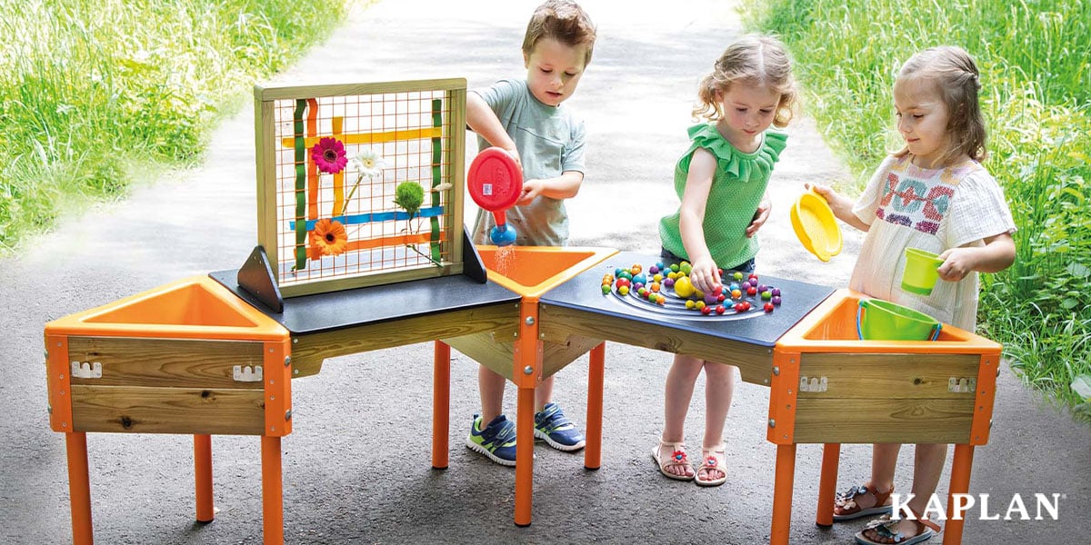 Featured image: Three preschool children engage in hands-on sensory play at an outdoor modular activity table - Read full post: How to Design Outdoor Learning Spaces For Early Learners