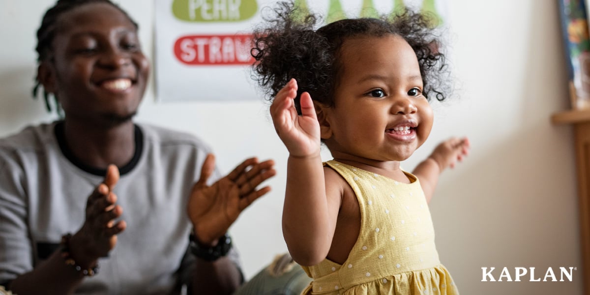 Featured image: A man in a gray shirt smiles and claps his hands while a young toddler in a yellow outfit stands, smiling with her arms out wide.  - Read full post: Strengthen Social-Emotional Skills in Early Learners with DECA