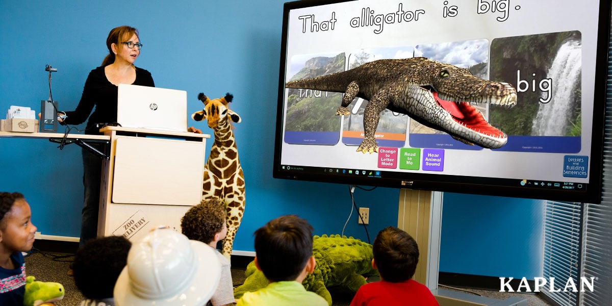 Featured image: An early childhood teacher stands in front of her classroom, children are sitting on the floor in front of her, looking up at an interactive panel screen featuring an image of a 3D alligator.  - Read full post: Using 3D Augmented Reality to Help Children Build Early Literacy and Math Skills