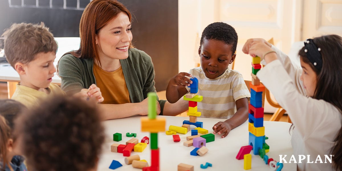 Featured image: Early childhood educator at a table with children building blocks - Read full post: How Does Kaplan Support Educators Using LAP™ and DECA?