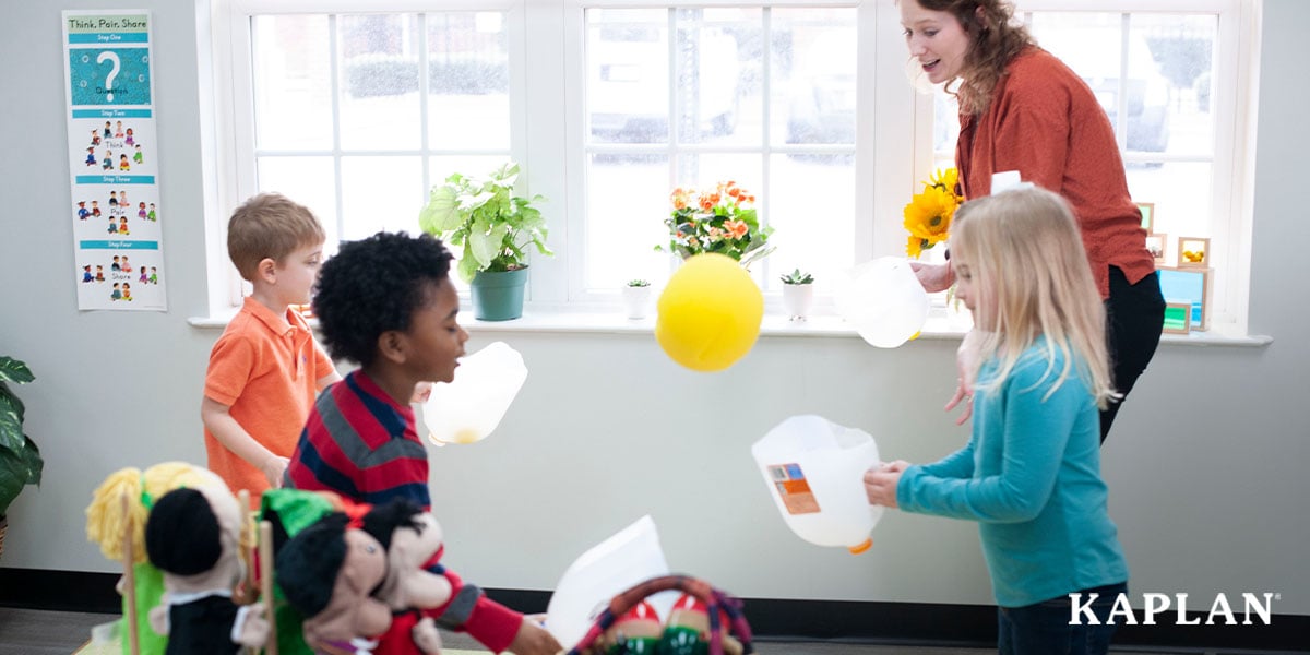 Featured image: An early childhood teacher and three young children stand in a circle in the middle of an early childhood classroom, they are all holding plastic milk jugs with the bottom cut off, a yellow balloon is floating in the air between them.  - Read full post: The Complete Guide to the Connect4Learning® Pre-K Curriculum